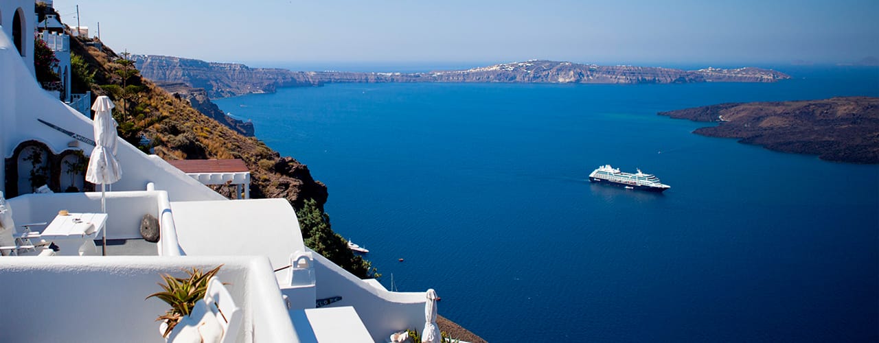 greece white buildings ocean and cruise boat in distance